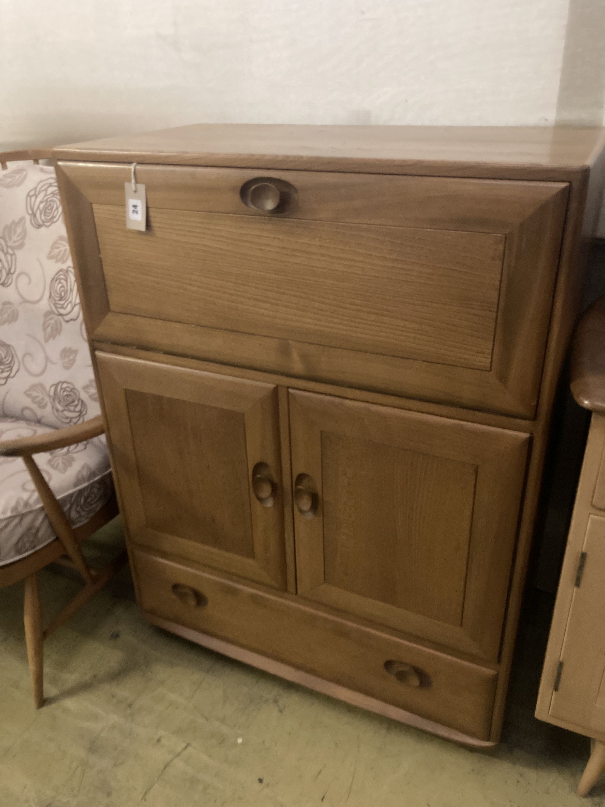 An Ercol elm drinks cabinet, fitted fall flap over cupboards and drawer, width 82cm depth 44cm height 110cm